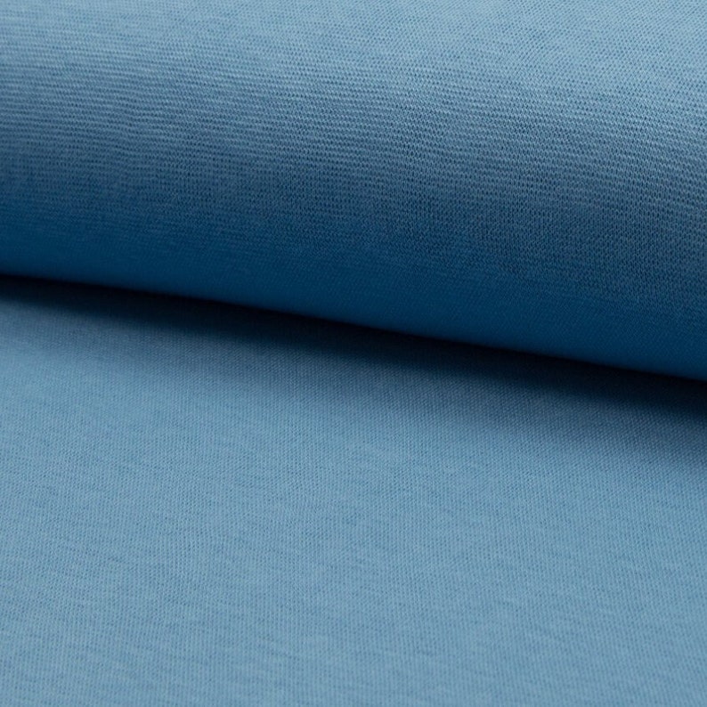 Op de afbeelding: Een close-up van een zachte, blauwe stof met een licht getextureerd oppervlak.