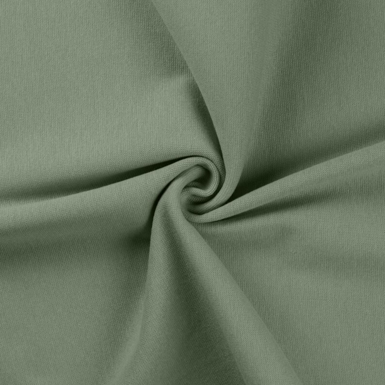 May include: A solid sage green fabric with a smooth, uniform texture. The material is gathered in the center, creating soft, flowing folds and deep shadows that highlight the consistent matte finish and the muted, earthy tone of the textile.