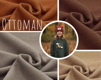 May include: A collage featuring four swatches of corduroy fabric in various shades of brown and tan. The word "OTTOMAN" is displayed in white text. A child wearing a green hoodie with a moon and cloud design is in the center.