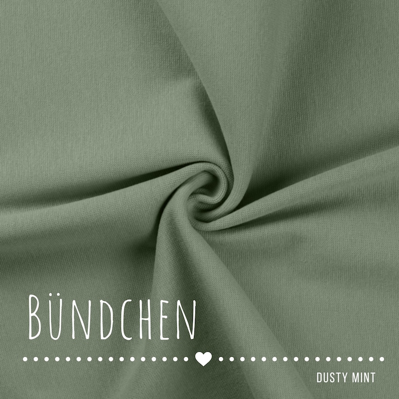 May include: A solid dusty mint green fabric with a smooth, fine-knit texture featuring soft folds and ripples. The text B&Uuml;NDCHEN is printed in white in the lower left corner, followed by a dotted line with a heart and the text DUSTY MINT.