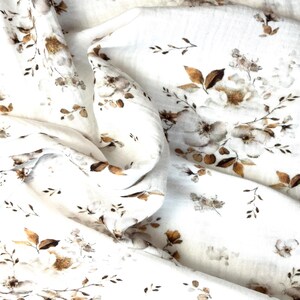 Puede incluir: Tela blanca con un patr&oacute;n floral marr&oacute;n. La tela es suave y tiene una textura delicada.