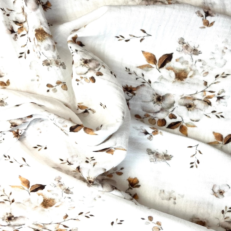 Puede incluir: Tela blanca con un patr&oacute;n floral marr&oacute;n. La tela es suave y tiene una textura delicada.