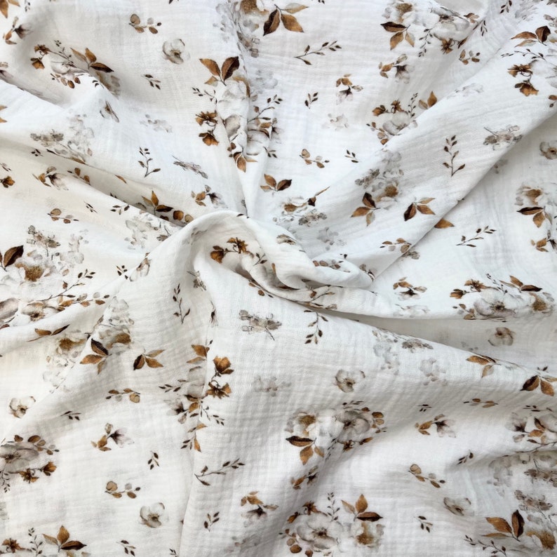 Puede incluir: Tela blanca con un patr&oacute;n floral marr&oacute;n. La tela es suave y tiene una textura arrugada.