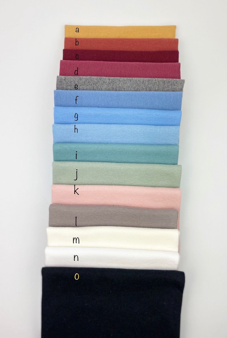 May include: A stack of 15 fabric swatches in various colors, including mustard yellow, red, burgundy, pink, gray, blue, and black. The swatches are labeled with letters from a to o.
