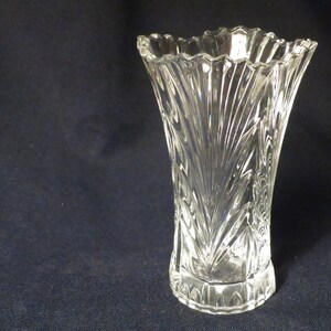 May include: A clear glass vase with a cut-glass design. The vase has a wide mouth and a narrow base.