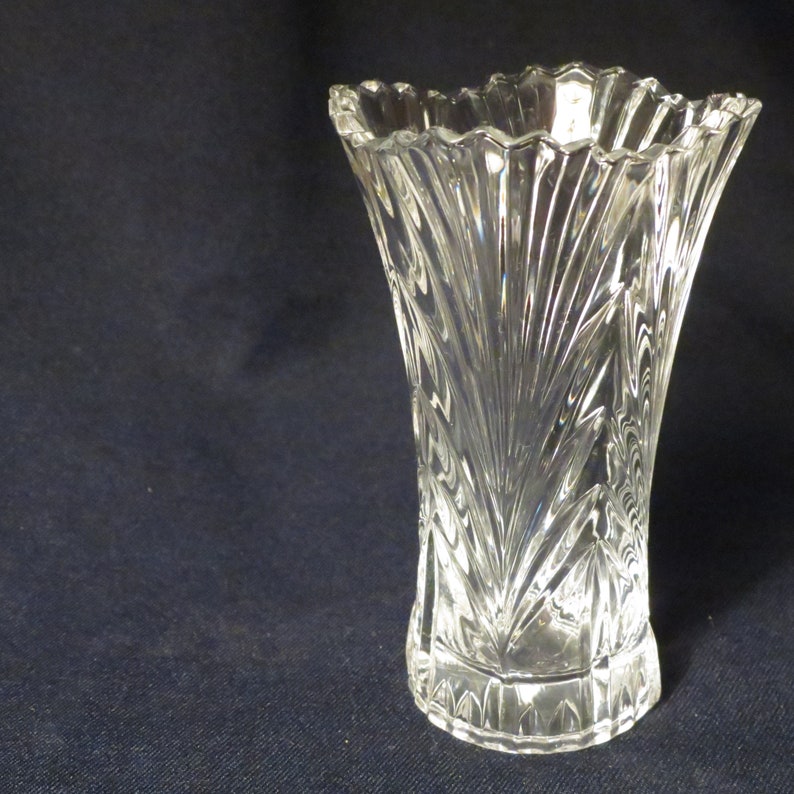 May include: A clear glass vase with a cut-glass design. The vase has a wide mouth and a narrow base.