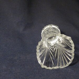May include: A clear glass vase with a scalloped rim and a diamond pattern. The vase is empty and has a reflective surface.