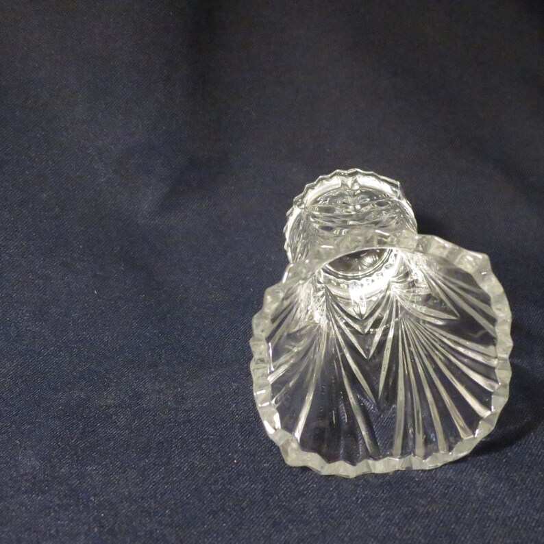 May include: A clear glass vase with a scalloped rim and a diamond pattern. The vase is empty and has a reflective surface.