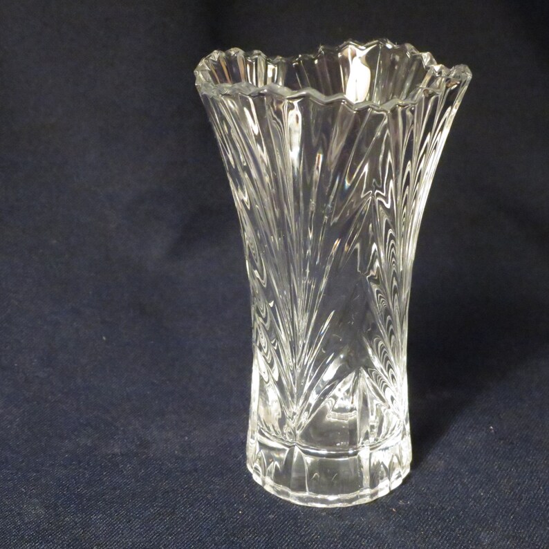 May include: A clear glass vase with a fluted design. The vase has a wide mouth and a narrow base.