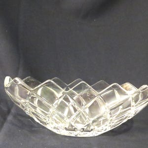May include: A clear, diamond-cut glass bowl with a scalloped rim. The bowl has a wide, oval shape and is designed with a repeating diamond pattern across its surface. The glass reflects light, creating a sparkling effect.