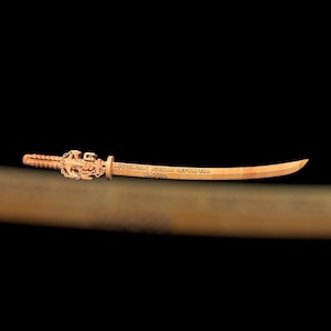 May include: A wooden katana with intricate carvings on the hilt and the text "LSC(SW/AW) JORDAN SEPULVEDA VAO-203" etched on the blade. The sword has a curved blade and a detailed handle, set against a dark background.