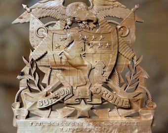Puede incluir: Tallado en madera detallado de un águila americana sobre un escudo con estrellas y un caballo. El tallado incluye banderas, ramas de laurel y el texto "SURSUM AB ORDINE" y nombres y fechas. Elaborado en madera clara.