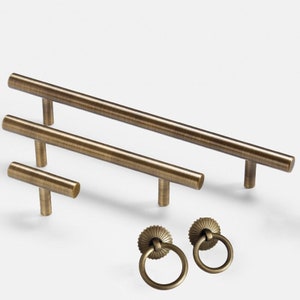 May include: Set of four antique brass cabinet hardware pulls.  Two long bar pulls, one short bar pull, and two round ring pulls with decorative accents.