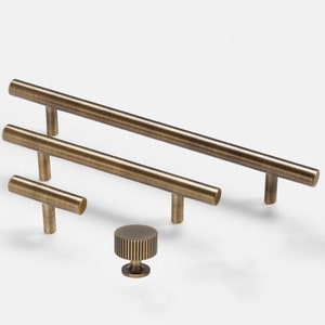 May include: Four antique brass cabinet pulls in various sizes, including a small round knob with a textured design.