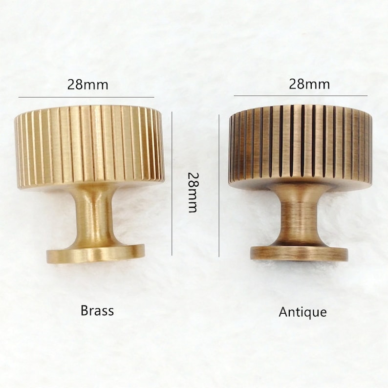 May include: Two round cabinet knobs with a fluted design. The knob on the left is brass and the knob on the right is antique brass. Both knobs are 28 mm in diameter.