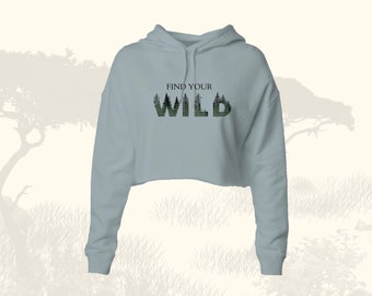 May include: A light blue cropped hoodie with long sleeves and a drawstring hood. The hoodie has the text "FIND YOUR WILD" printed on the front, with the word "WILD" made up of a silhouette of trees.
