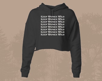 May include: A black cropped hoodie with long sleeves and a drawstring hood. The hoodie has the text "KEEP WOMEN WILD" repeated multiple times in white.