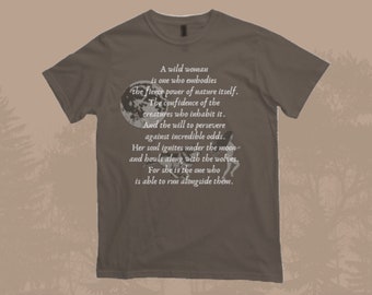 May include: A brown t-shirt with a full moon and two figures running under it. The text reads: "A wild woman is one who embodies the fierce power of nature itself. The confidence of the creatures who inhabit it. And the will to persevere against incredible odds. Her soul ignites under the moon and howls along with the wolves. For she is the one who is able to run alongside them."