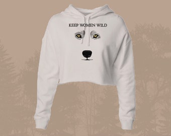 May include: White cropped hoodie with a wolf face graphic and the text "KEEP WOMEN WILD" printed on the front.