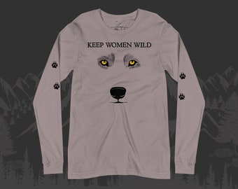 May include: A gray long-sleeve shirt with the text "KEEP WOMEN WILD" printed on the front. The shirt features a wolf's face with yellow eyes and a black nose. There are black paw prints on the sleeves.
