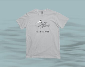 Może przedstawiać: Jasnoszary t-shirt z grafiką przedstawiającą kobietę pływającą z delfinami. Pod grafiką znajduje się napis "Find Your Wild".