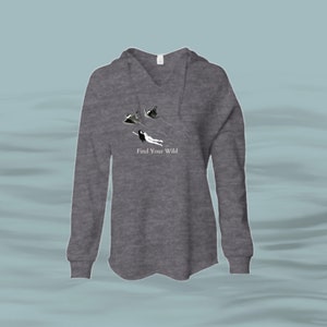 May include: Grey hooded sweatshirt with long sleeves and a V-neck. The front of the sweatshirt features a graphic of a person flying with birds and the text "Find Your Wild".