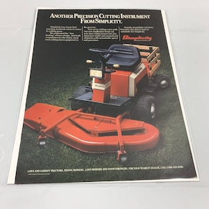 May include: A red and white Simplicity riding lawn mower with a rear-steer design. The mower has a large cutting deck and a wooden seat. The text "Another Precision Cutting Instrument From Simplicity" is printed at the top of the image. The text "Simplicity" is printed in a large font at the bottom of the image.