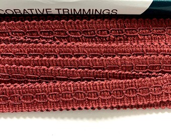 May include: Close-up of a red decorative trim with a woven pattern. The trim is labeled "Decorative Trimmings".