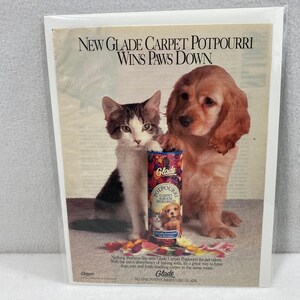 May include: An advertisement for Glade Carpet Potpourri featuring a kitten and a puppy. The product is a carpet and room deodorizer. The text reads "NEW GLADE CARPET POTPOURRI WINS PAWS DOWN."