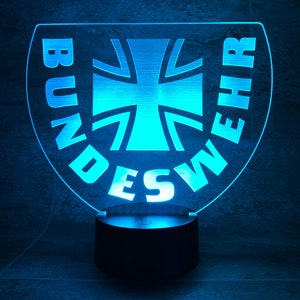 Könnte beinhalten: Ein blaues LED-Nachtlicht in Kreisform mit den Worten "BUNDESWEHR" am Rand und einem blauen Kreuz in der Mitte.