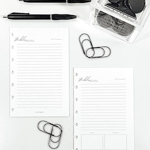 Peut inclure: Ensemble de papeterie comprenant deux stylos noirs, deux pages blanches lignées "Bible Notes", des trombones noirs et un récipient transparent contenant des aimants circulaires noirs. Les pages affichent "Bible Notes".