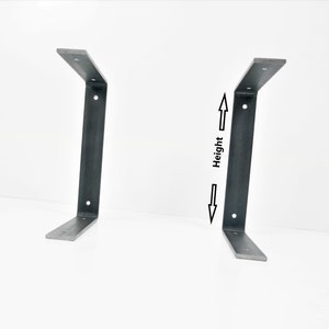 K&ouml;nnte beinhalten: Zwei schwarze Metall-Regalhalterungen mit einem 90-Grad-Winkel. Die Halterungen sind vor einem wei&szlig;en Hintergrund abgebildet. Die H&ouml;he der Halterungen ist beschriftet.