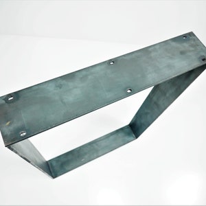 K&ouml;nnte beinhalten: Ein quadratisches Tischbein aus Metall. Das Bein ist aus Stahl und hat eine rohe, unfertige Optik.