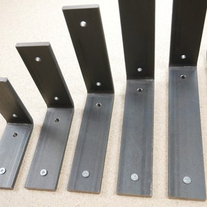 May include: A set of six dark gray metal shelf brackets in varying sizes. Each L-shaped bracket has pre-drilled holes for mounting and includes a silver screw. The brackets are designed for supporting shelves and are made of sturdy metal.