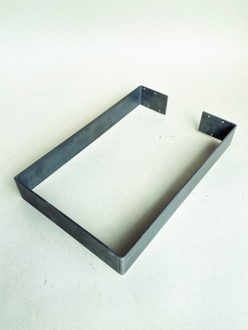 May include: A metal frame with a rectangular shape. The frame is made of a single piece of metal that is bent into a rectangle. The frame is open on one side.