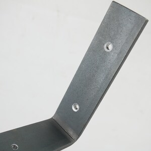 Puede incluir: Un soporte de estante de metal plateado con tres agujeros preperforados. El soporte est&aacute; doblado en un &aacute;ngulo de 90 grados.