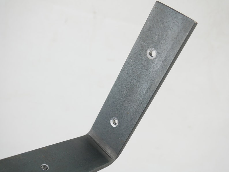 Puede incluir: Un soporte de estante de metal plateado con tres agujeros preperforados. El soporte est&aacute; doblado en un &aacute;ngulo de 90 grados.