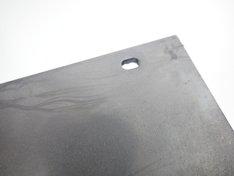 K&ouml;nnte beinhalten: Nahaufnahme einer grauen Metallplatte mit einem kleinen Loch in der Mitte. Die Platte hat eine strukturierte Oberfl&auml;che und scheint leicht verkratzt zu sein.