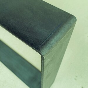 May include: A dark gray concrete shelf unit with a rounded edge. The shelf is empty and has a rough texture.