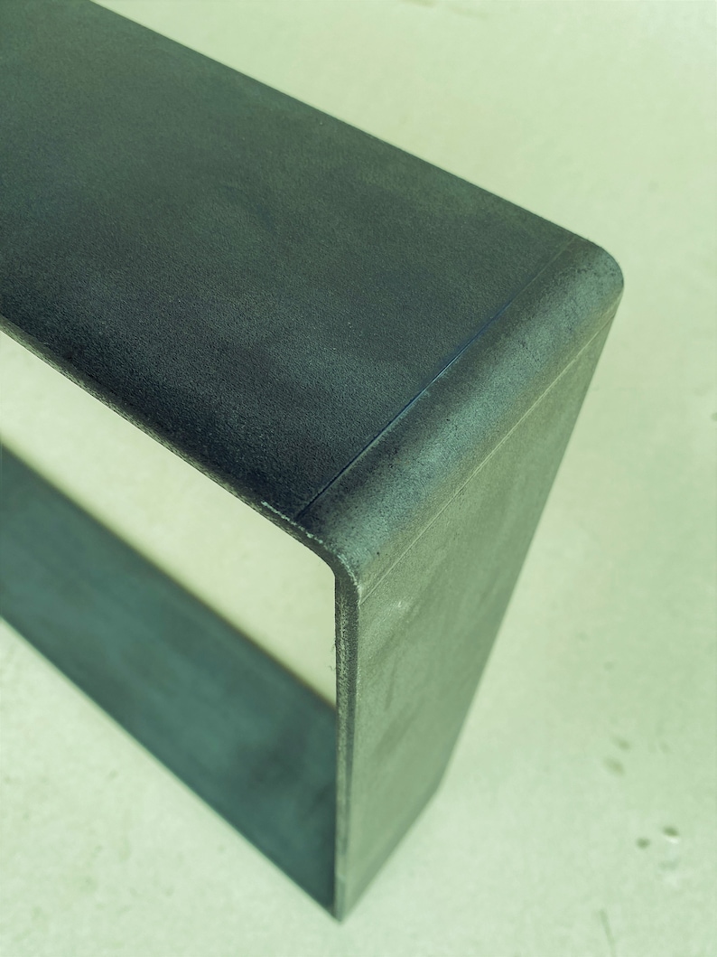 May include: A dark gray concrete shelf unit with a rounded edge. The shelf is empty and has a rough texture.