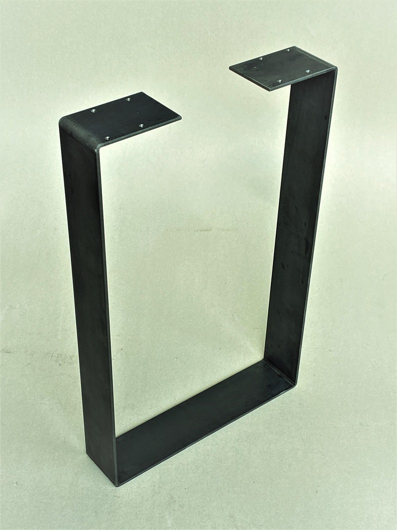 May include: Black metal table leg with a rectangular shape and a welded seam. The leg is made of thick metal and has a simple, industrial design.