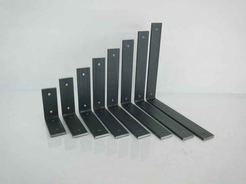 May include: A collection of eight dark gray metal shelf brackets of varying sizes. Each bracket has a right-angle design with pre-drilled holes for mounting. The brackets are arranged in a row, showcasing their different lengths and widths.