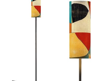 May include: A tall floor lamp with a cylindrical lampshade featuring an abstract design. The shade displays a mix of colors, including red, yellow, black, and white. The lamp has a dark metal pole and a round base.