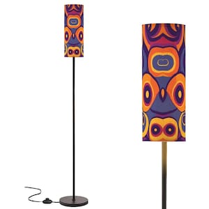 May include: A tall, black floor lamp with a cylindrical lampshade. The lampshade features a repeating pattern of orange, yellow, and purple abstract shapes. The lamp has a round base and a foot switch.