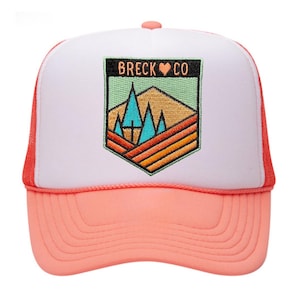May include: White and pink trucker hat with a patch that says "Breck ♥ Co" and features a mountain range with trees.