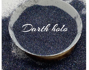 May include: A close-up of a bowl filled with black glitter with iridescent holographic flakes. The text "Darth Holo" is written in white cursive on the glitter.