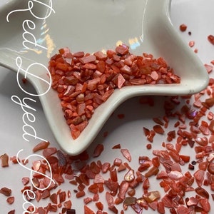 May include: Red dyed pearl chips in a white star-shaped dish. The chips are small and irregular in shape. The text "$2-1 oz" is visible in the image.