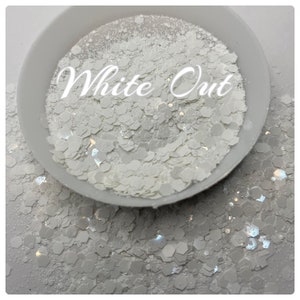 May include: White glitter in a small white bowl. The glitter is in a variety of shapes and sizes, and it has a iridescent finish. The bowl is sitting on a white surface. The text "White Out" is written in black letters on the bowl.