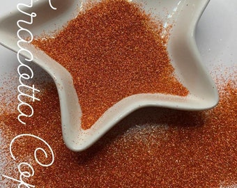 May include: Terracotta Copper fine glitter in a white star-shaped dish. The glitter is a warm orange color with a slight shimmer.