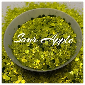 May include: A close-up of a bowl filled with green and gold glitter, labeled "Sour Apple".